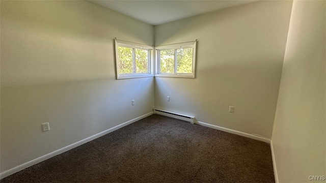 unfurnished room with a baseboard heating unit and dark colored carpet