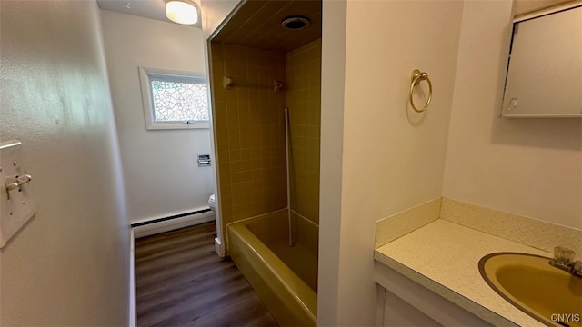 full bathroom with hardwood / wood-style flooring, toilet, baseboard heating, tiled shower / bath combo, and vanity