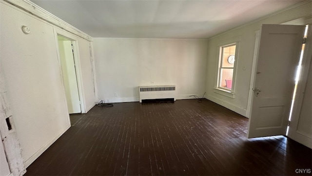 unfurnished living room featuring crown molding, radiator heating unit, and dark wood-type flooring