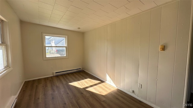 spare room featuring wooden walls, dark hardwood / wood-style flooring, and baseboard heating