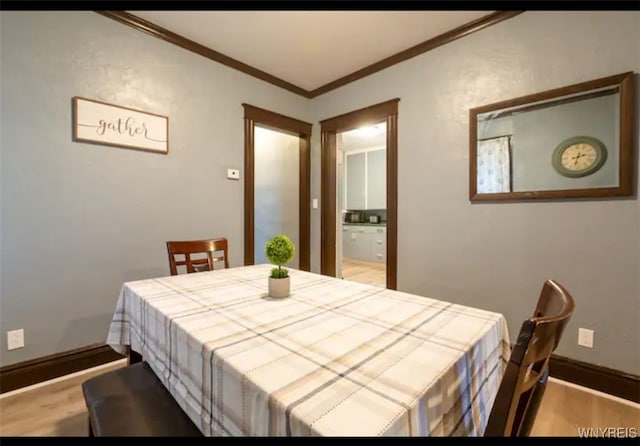 dining room with crown molding and light wood-type flooring