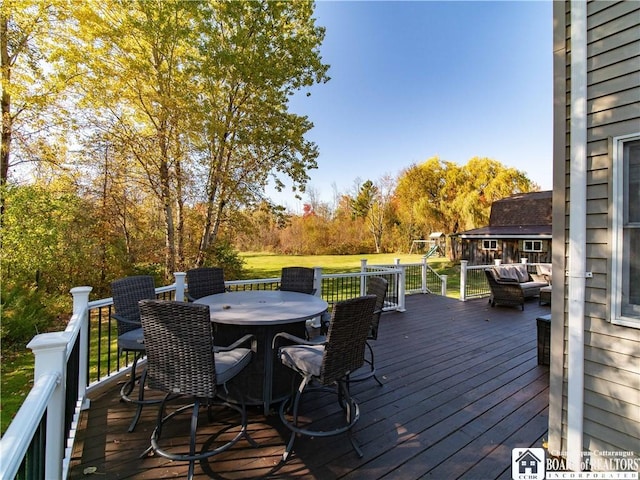 wooden terrace with outdoor dining space and a lawn