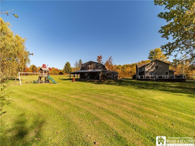 view of yard with an outdoor structure, a playground, and a barn