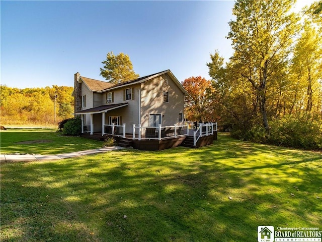 rear view of property featuring a wooden deck and a lawn