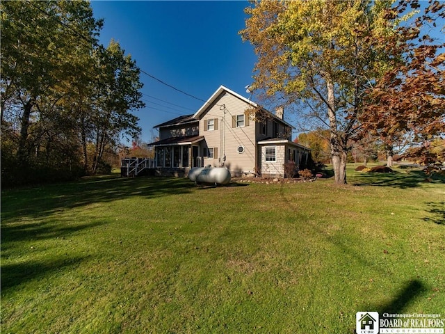 exterior space featuring a lawn, a chimney, and a sunroom