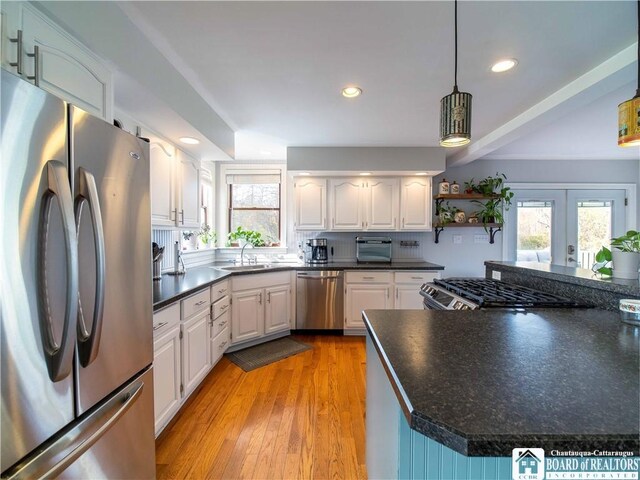 kitchen with decorative light fixtures, sink, white cabinets, stainless steel appliances, and light wood-type flooring