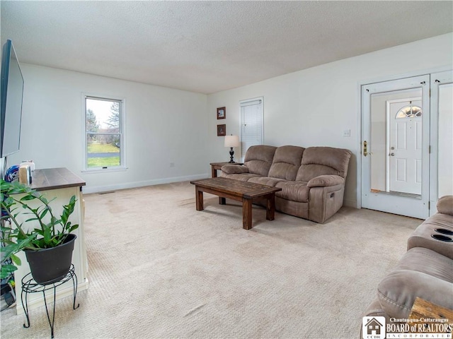 living area featuring light colored carpet, baseboards, and a textured ceiling