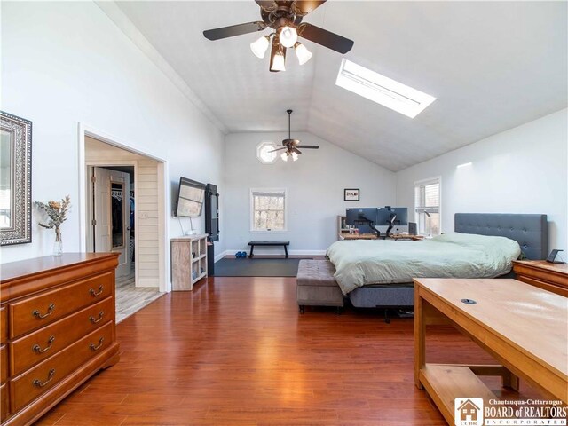 bedroom with dark wood-type flooring, vaulted ceiling with skylight, and ceiling fan