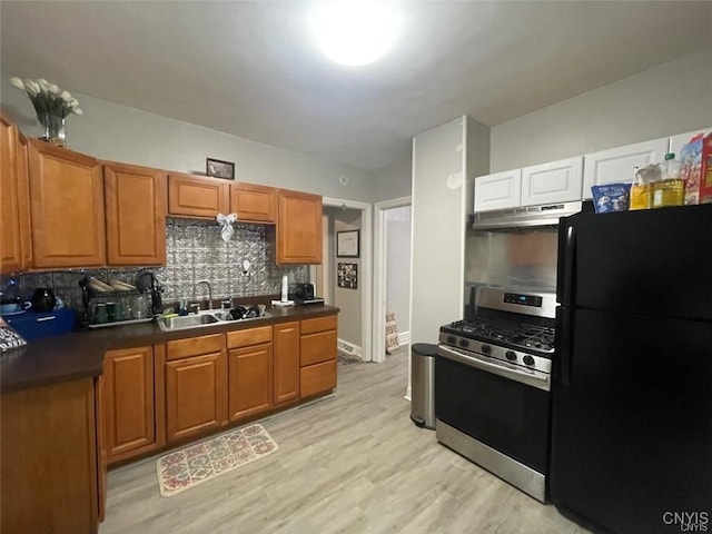 kitchen featuring tasteful backsplash, gas range, light hardwood / wood-style flooring, black refrigerator, and sink