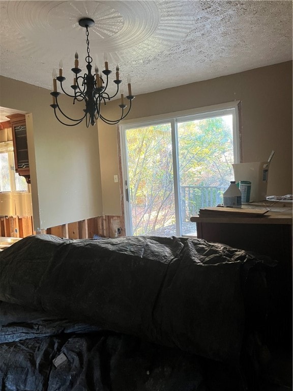 interior space featuring multiple windows, wooden walls, a chandelier, and a textured ceiling