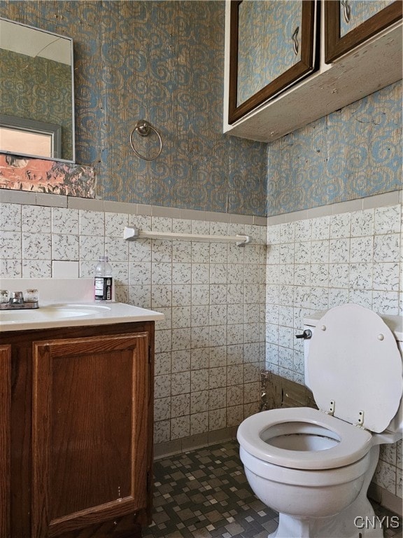 bathroom featuring toilet, vanity, and tile walls