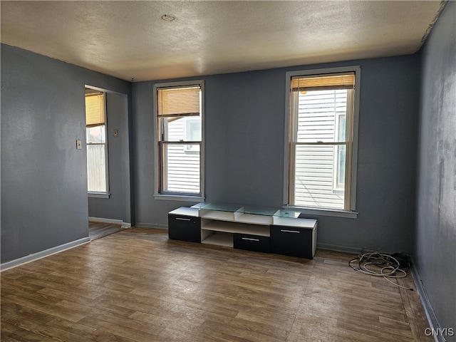 unfurnished room featuring dark hardwood / wood-style flooring, a textured ceiling, and a wealth of natural light