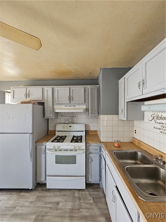 kitchen featuring white appliances, decorative backsplash, light hardwood / wood-style flooring, and sink