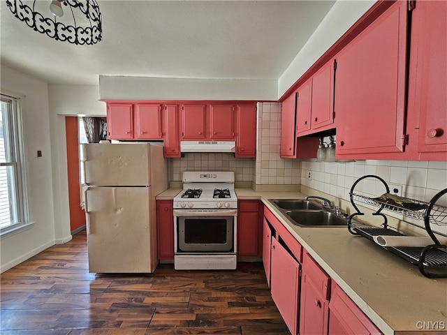 kitchen featuring white appliances, backsplash, dark wood-type flooring, and sink