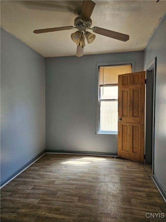 empty room with ceiling fan and dark hardwood / wood-style flooring