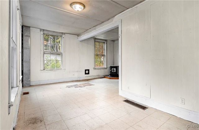 empty room featuring a wood stove and plenty of natural light