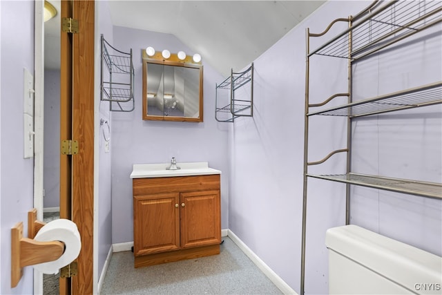 bathroom featuring vanity, toilet, and vaulted ceiling