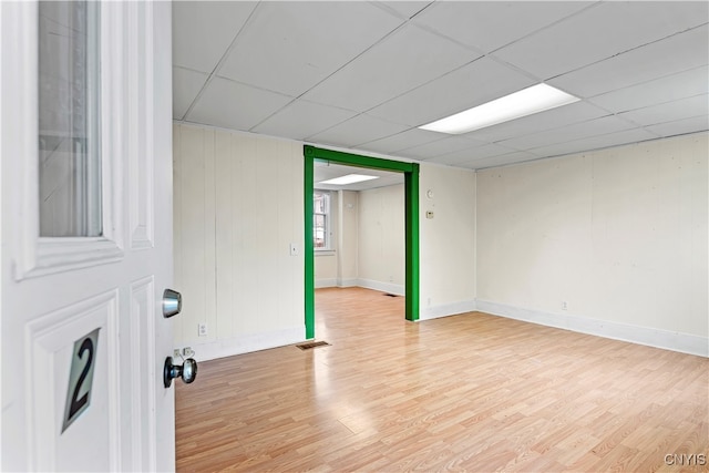 spare room featuring light hardwood / wood-style flooring and a drop ceiling