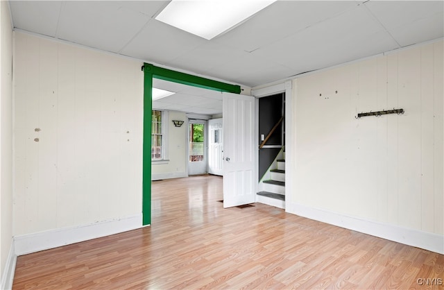 empty room with light hardwood / wood-style floors and wooden walls