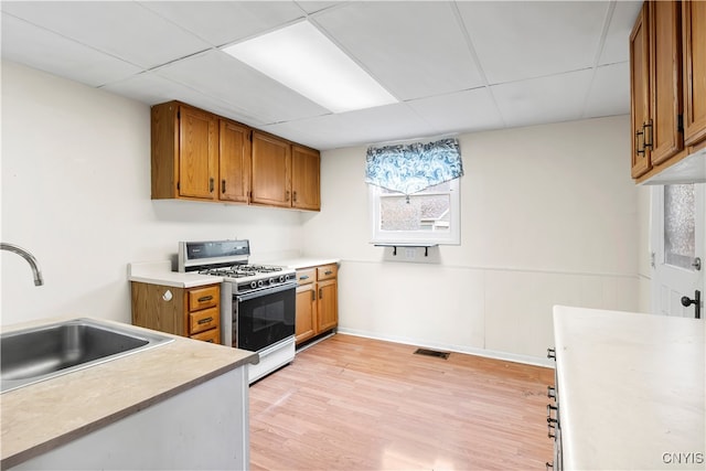 kitchen featuring light hardwood / wood-style floors, white range with gas cooktop, sink, and a drop ceiling