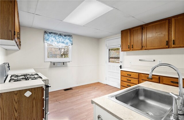 kitchen with sink, white range with gas cooktop, and light hardwood / wood-style flooring