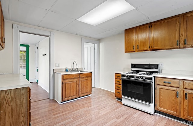 kitchen with sink, white gas range oven, a paneled ceiling, and light hardwood / wood-style floors