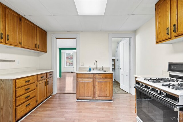 kitchen with sink, light hardwood / wood-style flooring, and white gas range oven