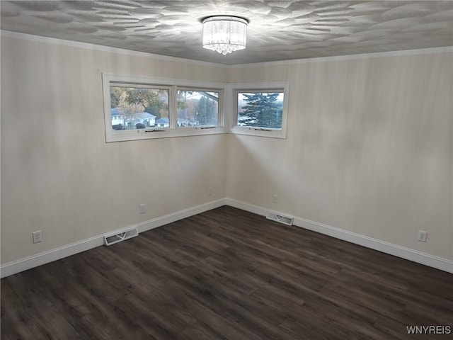 empty room with ornamental molding, dark wood finished floors, and visible vents