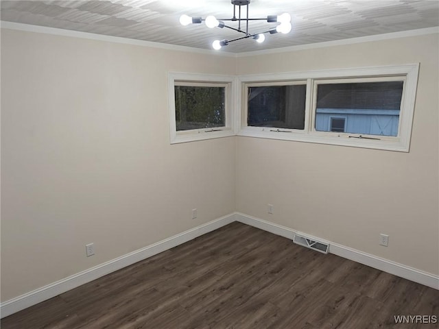 unfurnished room with a chandelier, visible vents, baseboards, ornamental molding, and dark wood-style floors