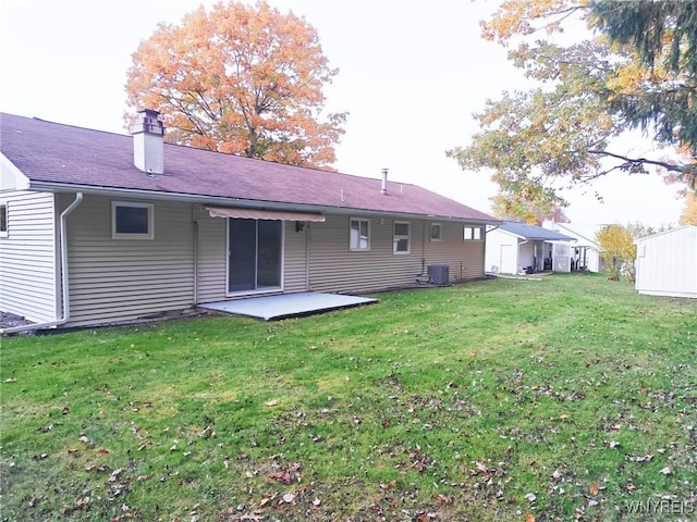 back of house with a yard, central AC, a patio, and a chimney