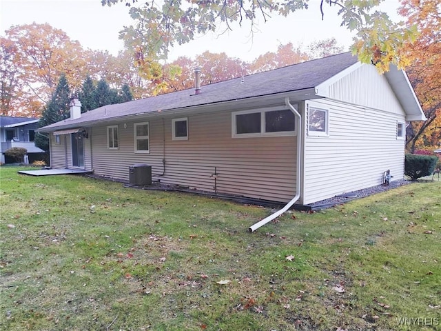 rear view of property featuring a lawn, a chimney, and central air condition unit