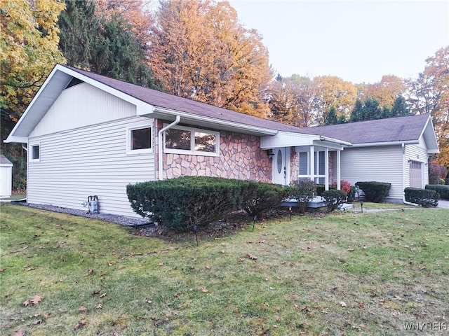 view of front facade featuring stone siding, an attached garage, and a front lawn