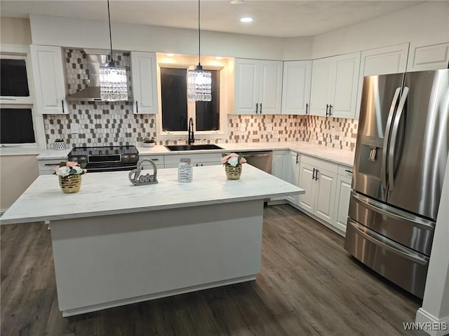 kitchen with a kitchen island, hanging light fixtures, stainless steel appliances, white cabinetry, and a sink