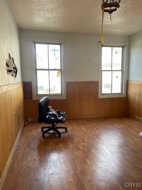 unfurnished room with hardwood / wood-style floors, a textured ceiling, and wood walls