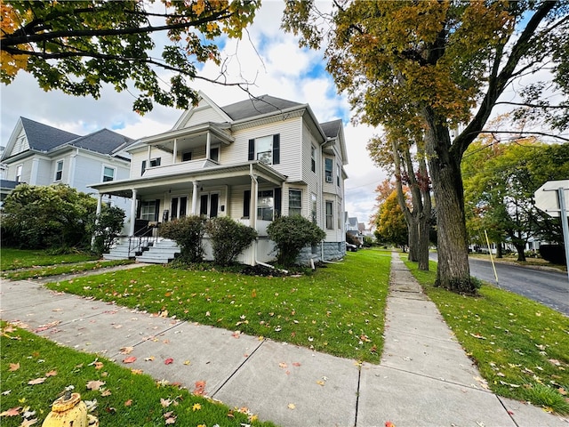 view of property with covered porch and a front yard