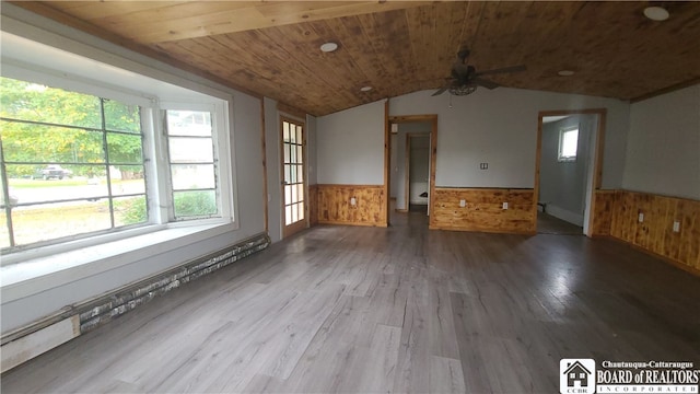 spare room with wooden walls, wooden ceiling, wood-type flooring, and vaulted ceiling