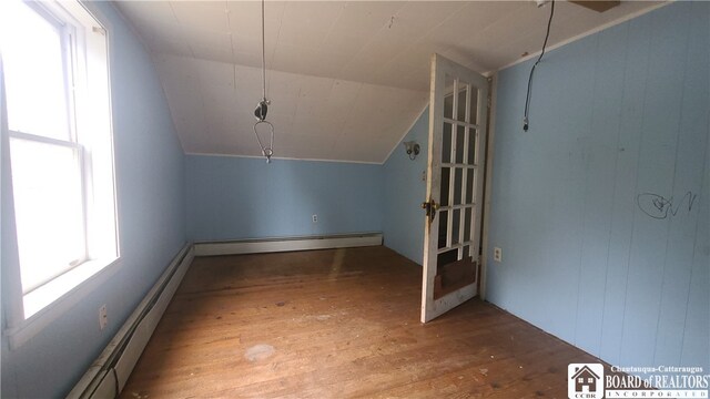 additional living space featuring wood-type flooring, a baseboard radiator, and vaulted ceiling