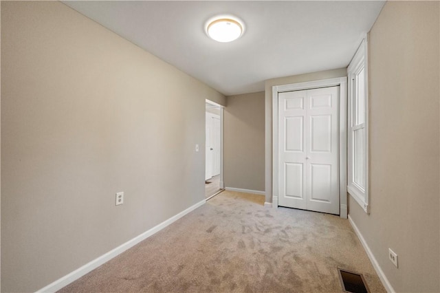 unfurnished bedroom featuring light colored carpet and a closet