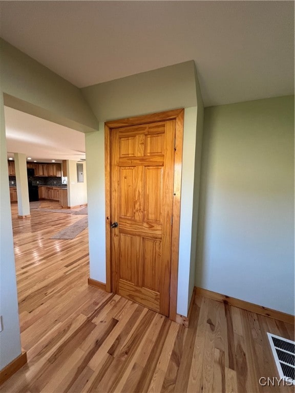 hallway with light hardwood / wood-style floors and vaulted ceiling