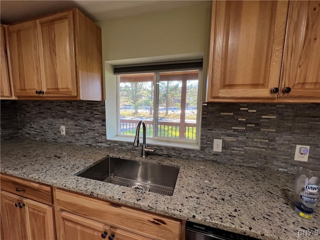 kitchen featuring light stone counters, decorative backsplash, and sink