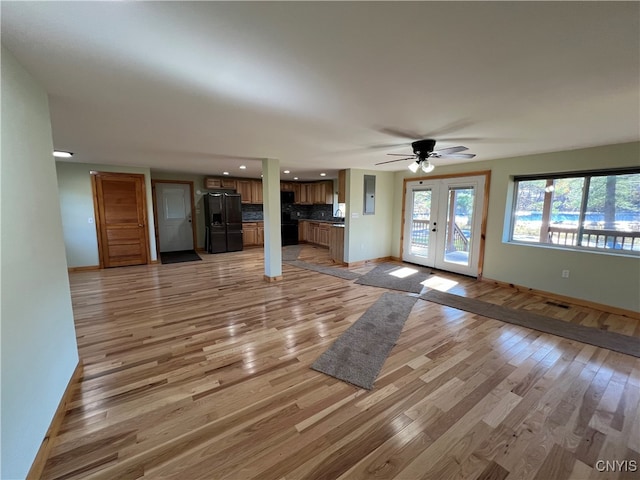 unfurnished living room with french doors, light wood-type flooring, and ceiling fan