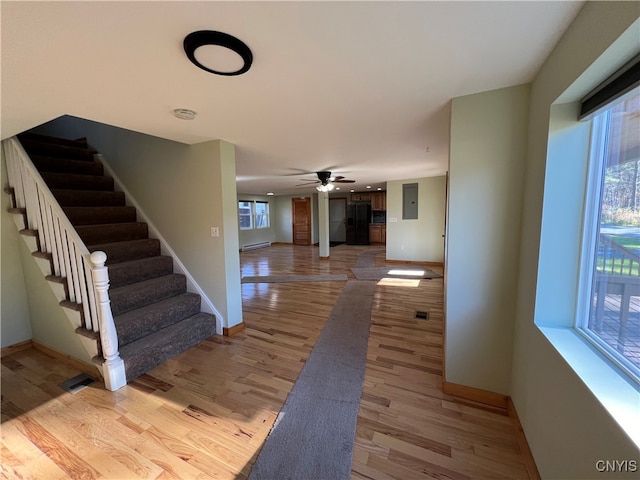 hall with baseboard heating, electric panel, light hardwood / wood-style flooring, and plenty of natural light