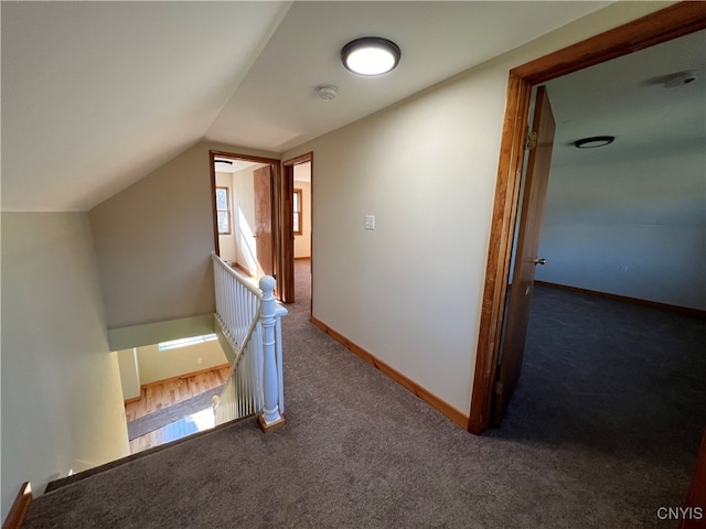 corridor featuring dark carpet and vaulted ceiling