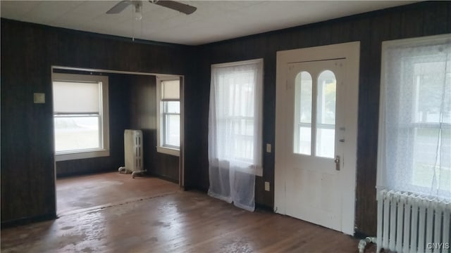 entryway featuring wood-type flooring, radiator, and wooden walls