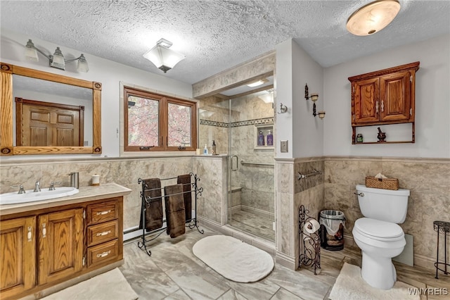 bathroom with vanity, tile walls, a shower with shower door, and toilet