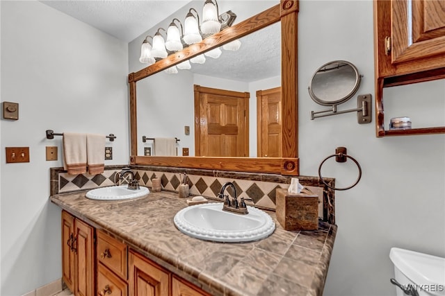 bathroom with vanity, toilet, decorative backsplash, and a textured ceiling