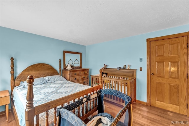 bedroom featuring light hardwood / wood-style floors and a textured ceiling