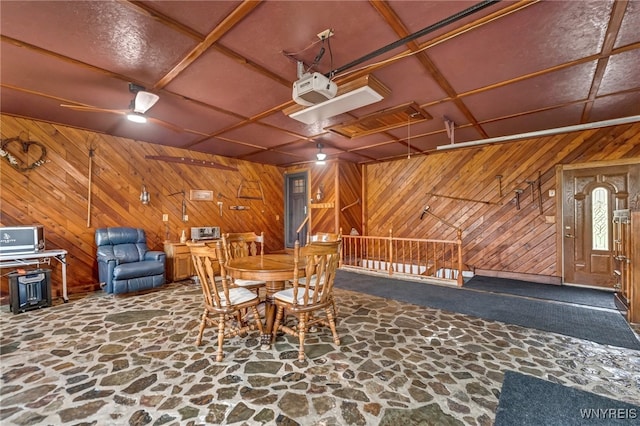 unfurnished dining area featuring ceiling fan and wood walls