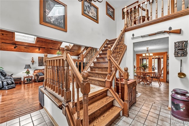 stairway with hardwood / wood-style flooring, an inviting chandelier, and a skylight