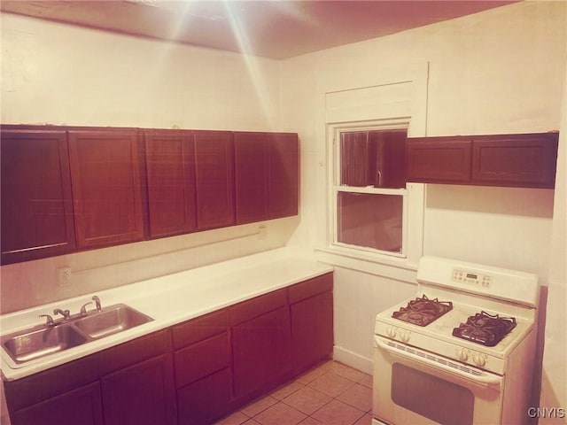 kitchen with light tile patterned floors, white gas range, and sink